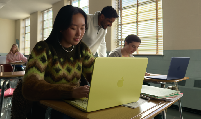Una estudiante usa una MacBook Neo, color amarillo cítrico, sin enchufar a la corriente en un salón de clases