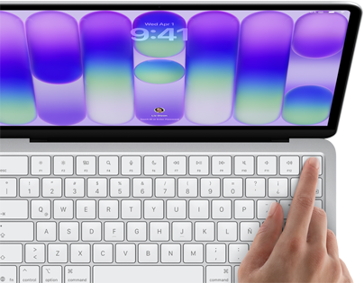 MacBook Neo, color plata, muestra la pantalla de inicio de sesión, el dedo de una persona en el sensor de Touch ID en la esquina superior derecha del teclado